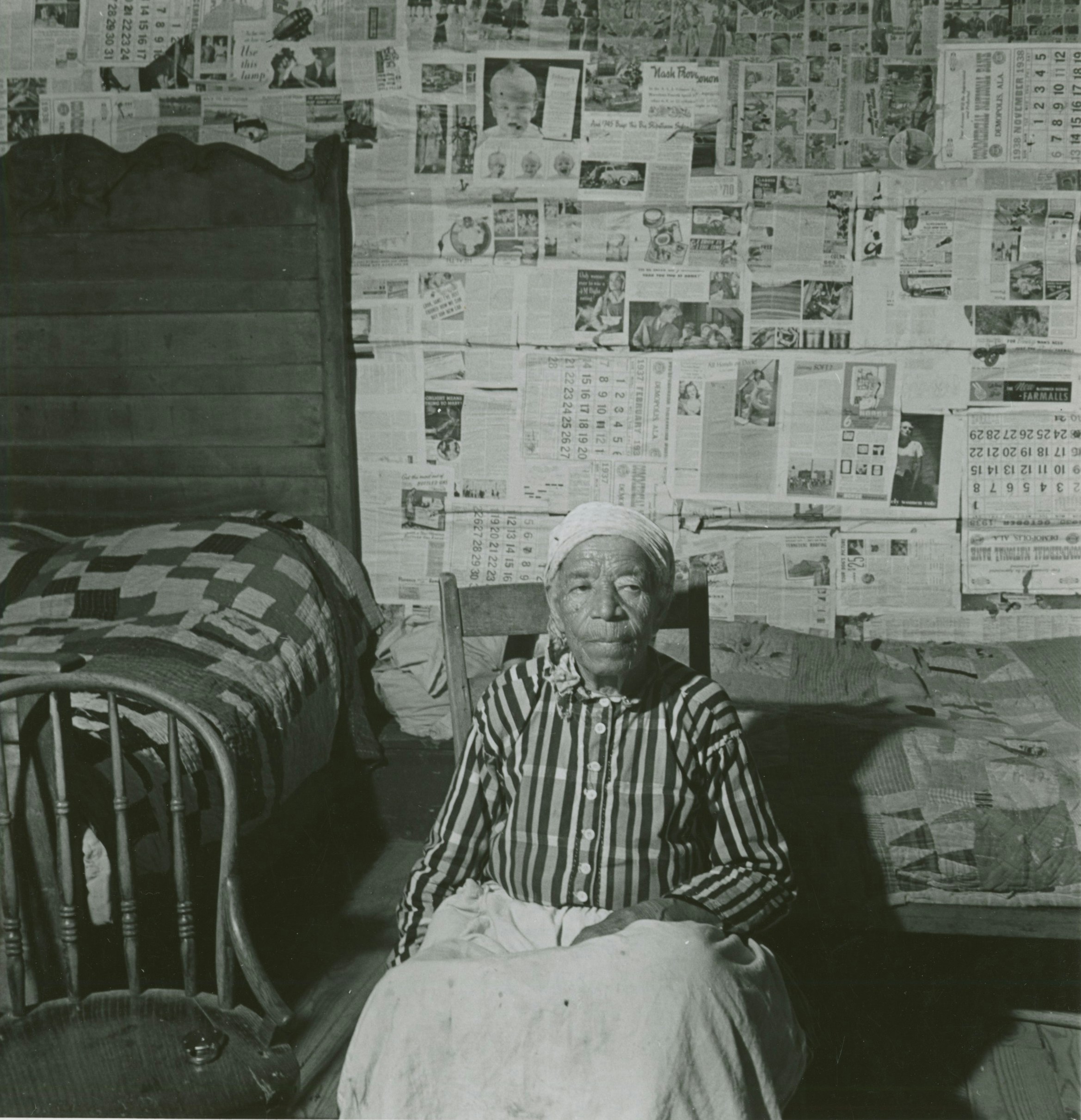 man sitting on chair beside bed and near chair